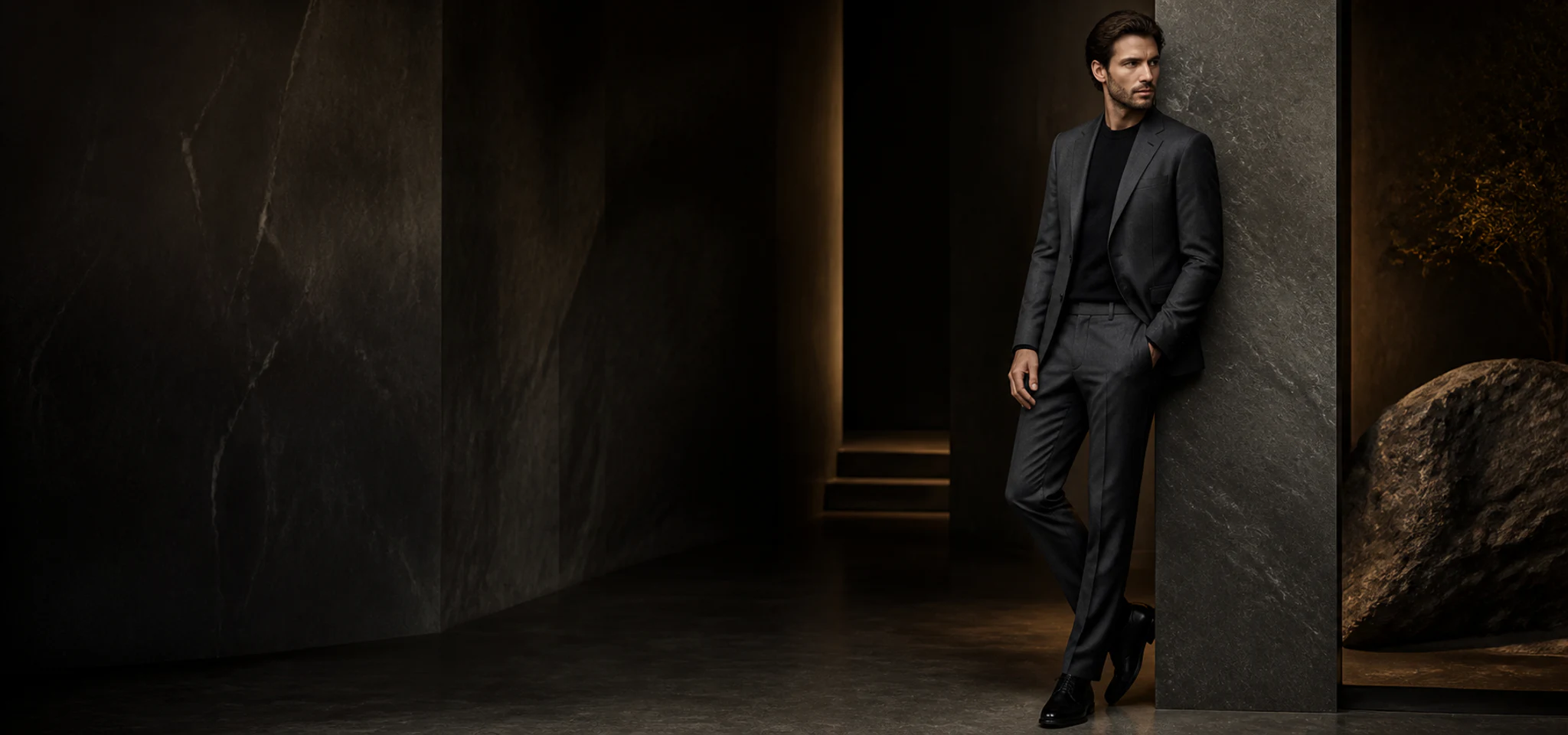 Homme portant un costume anthracite dans un décor architectural sombre
